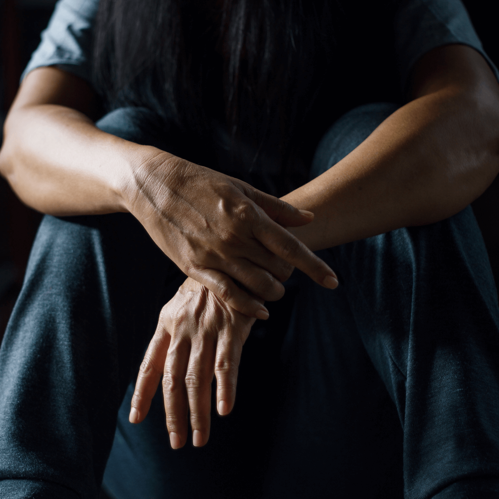 Depressed woman sitting alone on the floor in a dark room