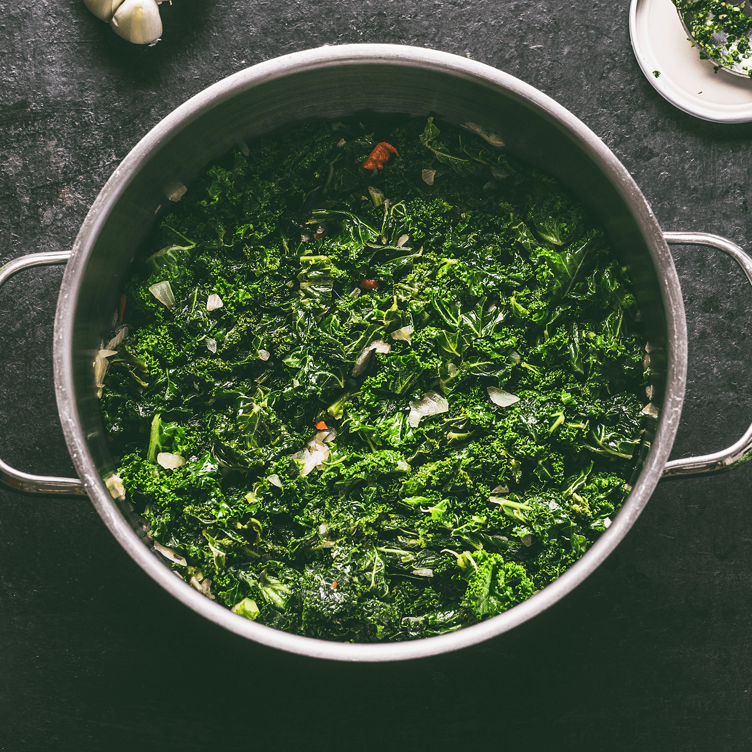 Stewed kale in cooking pot on dark kitchen table background