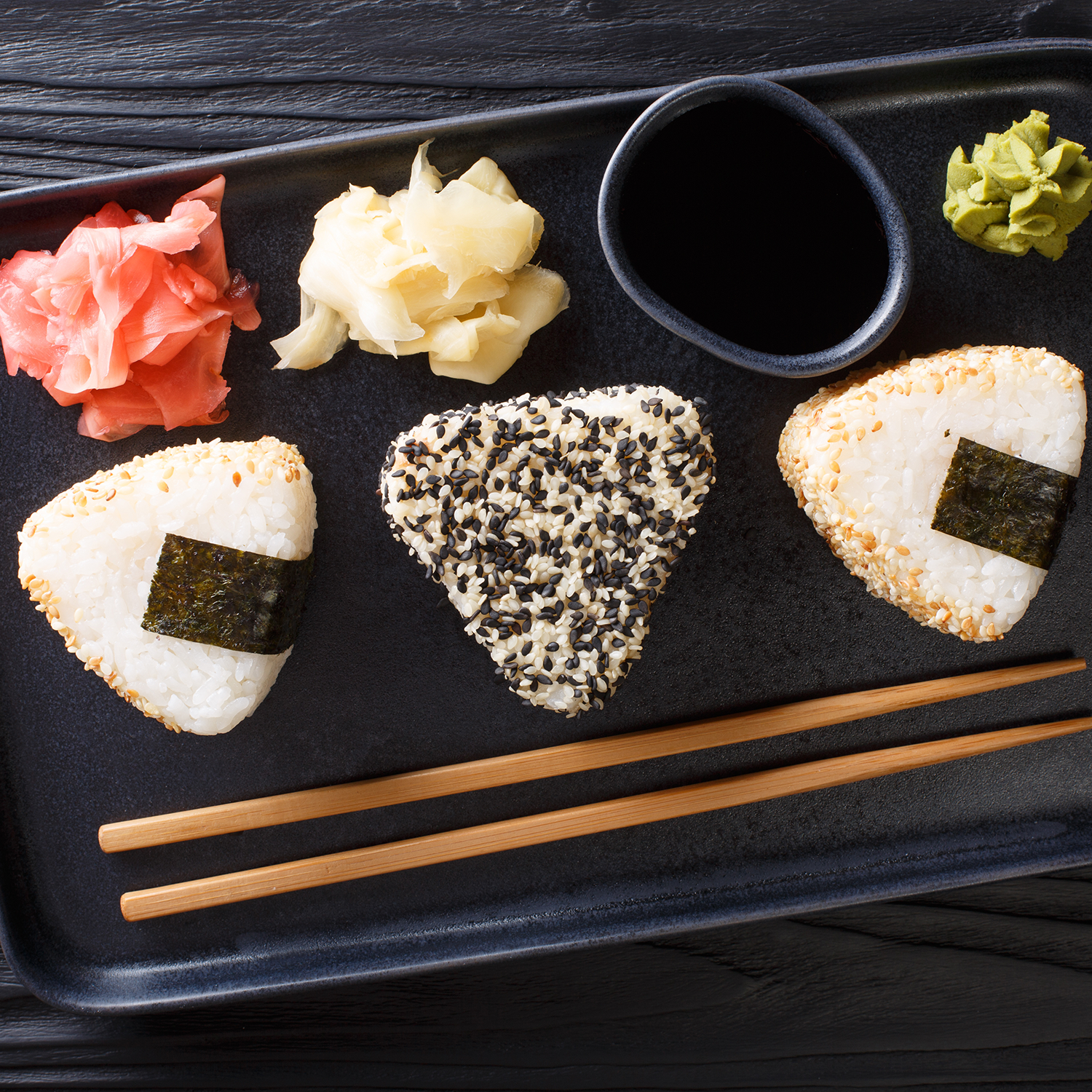 Three onigiri rice balls on a black plate