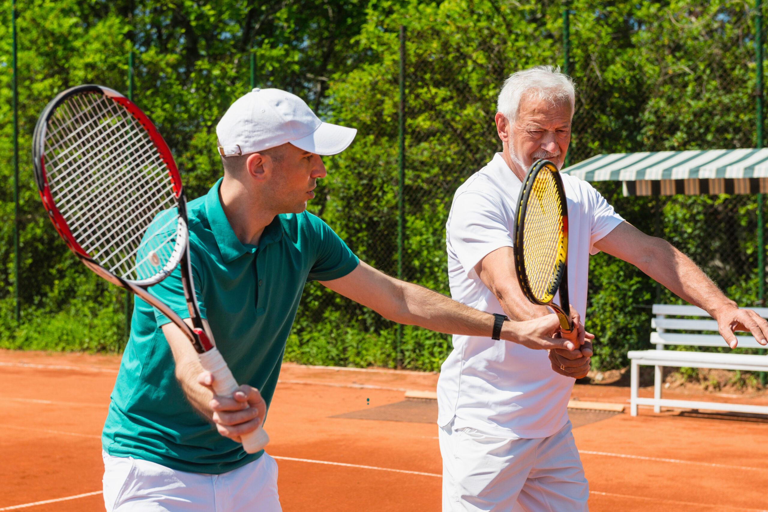 Tennis instructor working with a senior adult on a tennis court