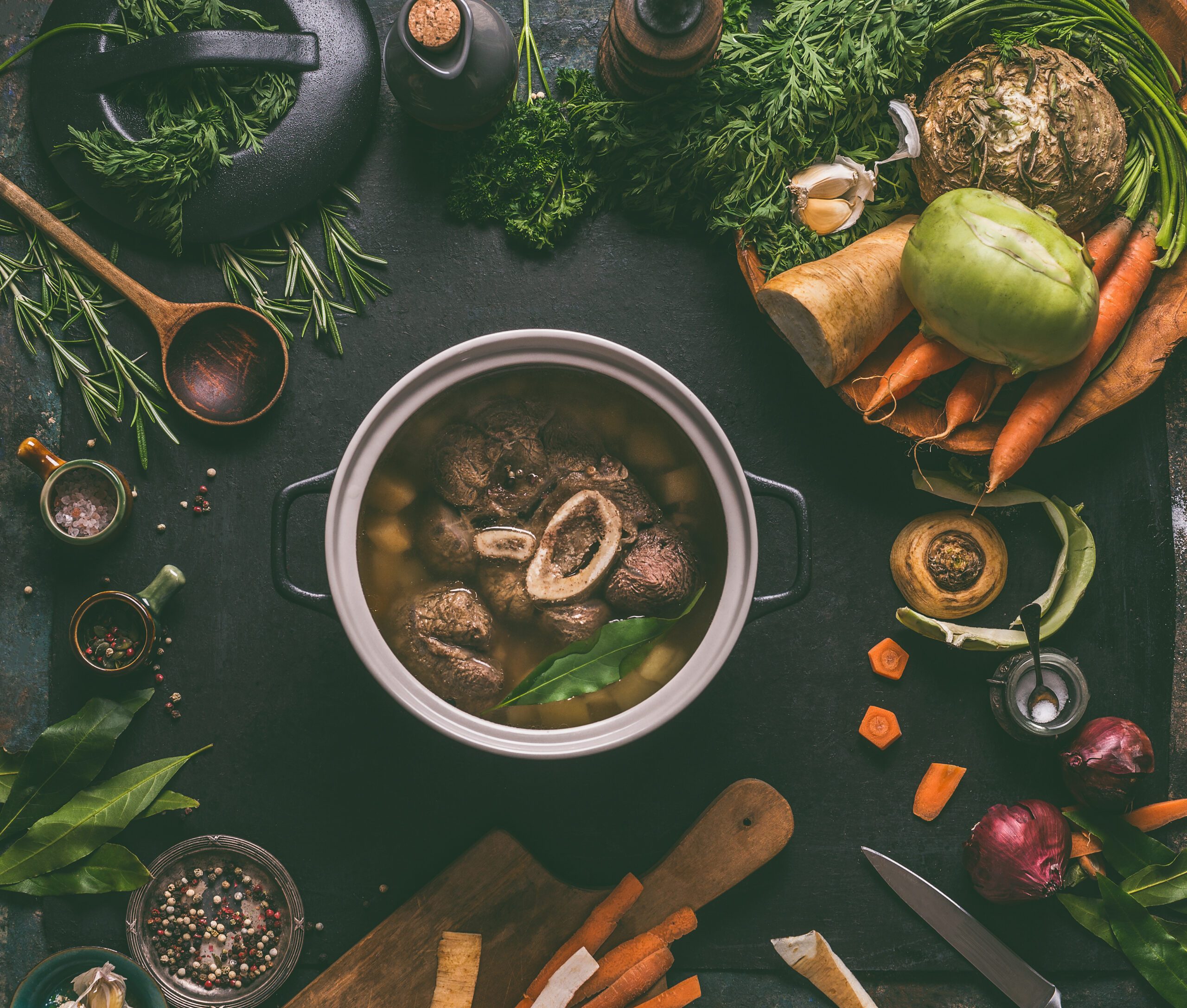 Cooked beef with bone in a cooking pot on a dark kitchen table