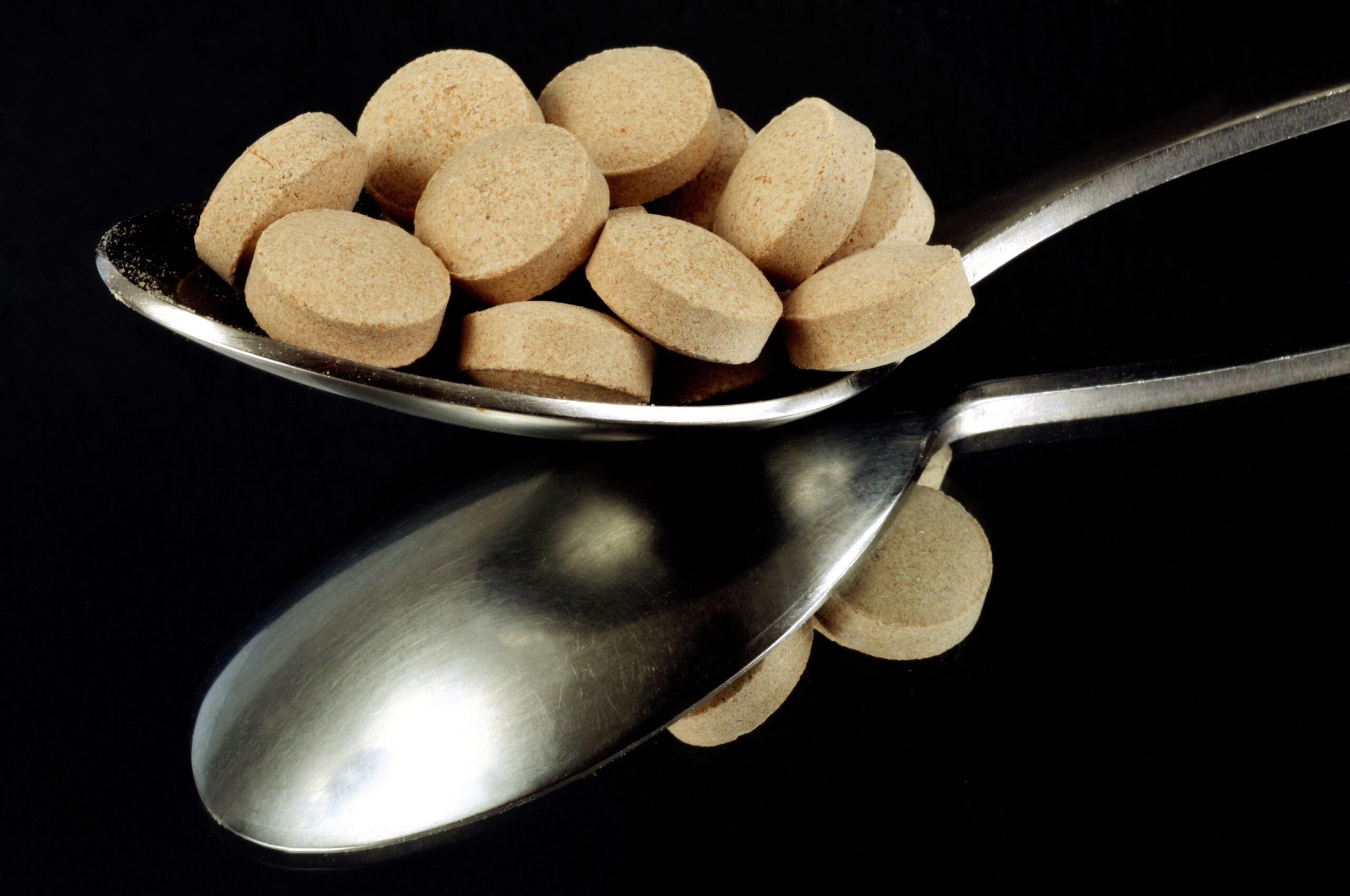 Pile of tan pills in a spoon