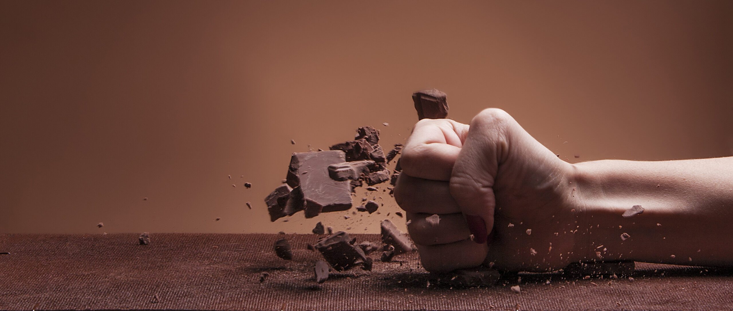 Hand destroying a block of chocolate