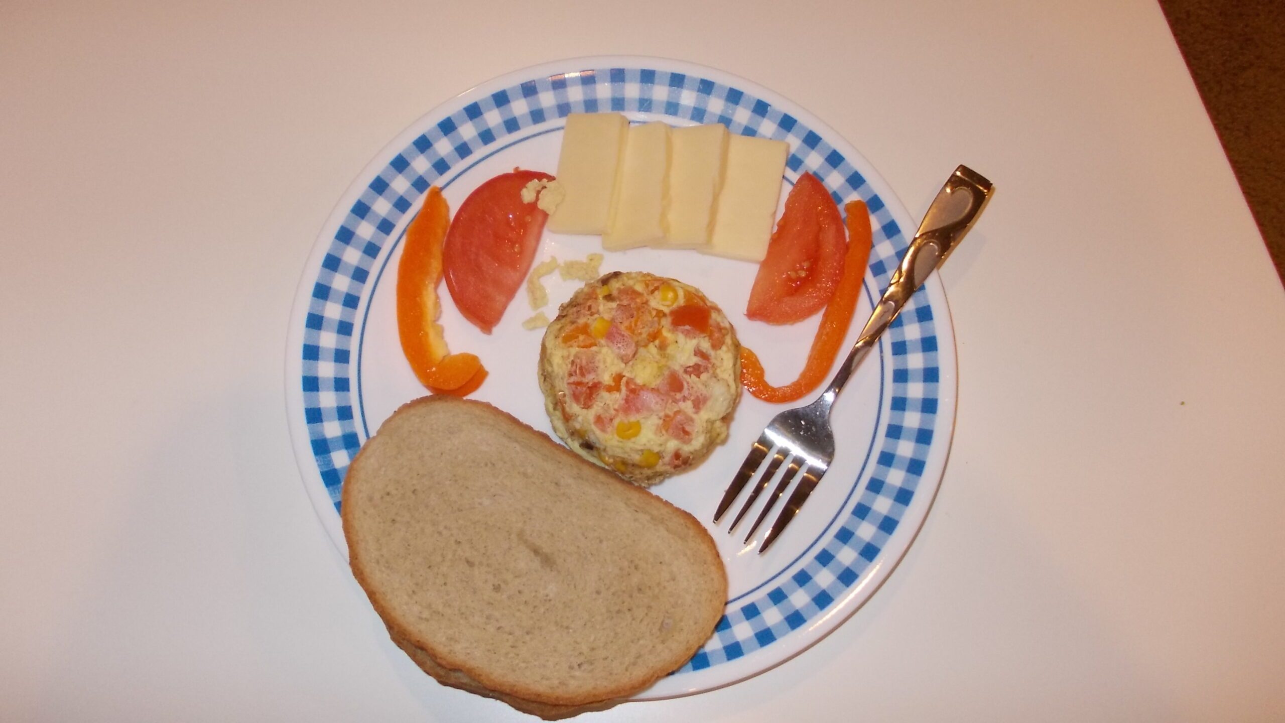 Microwave omelet on a plate with a slice of bread, cheese, and tomatoes