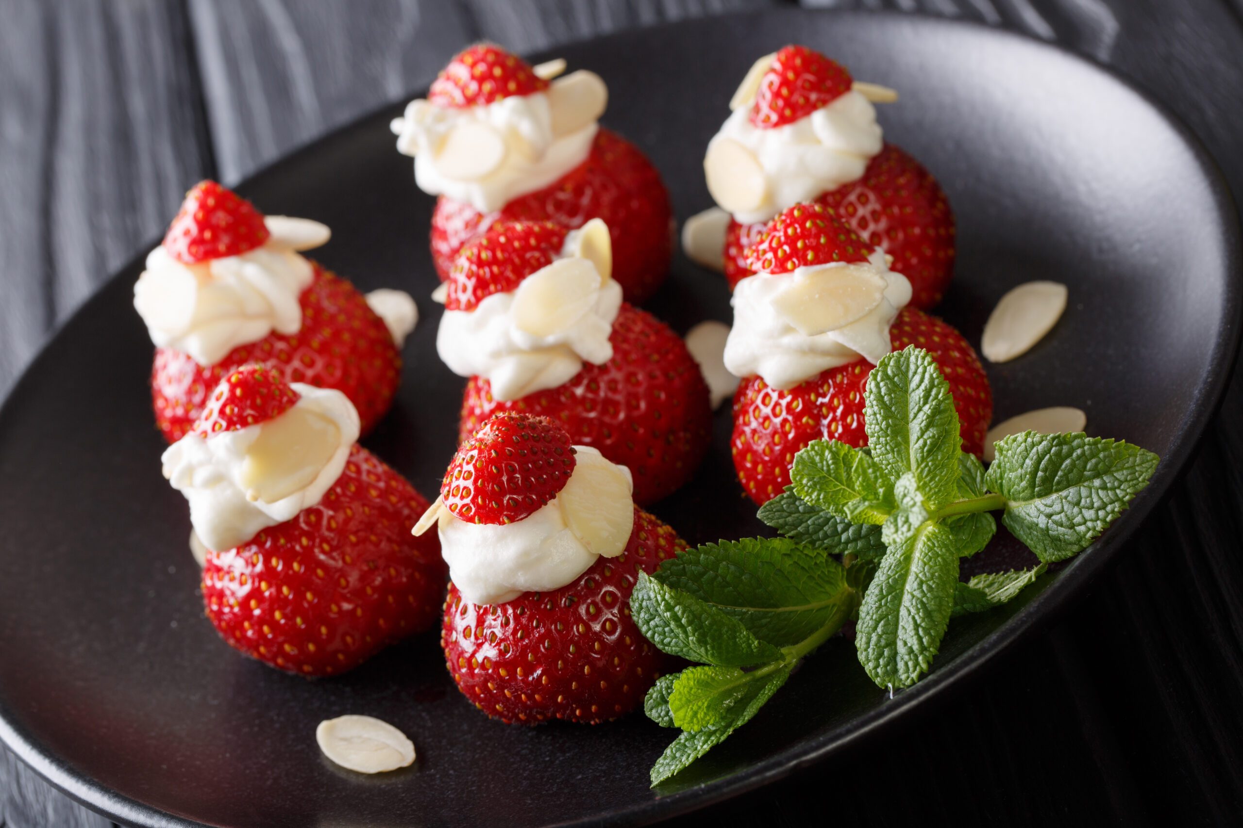 Fresh strawberries with almonds and whipped cream on a plate