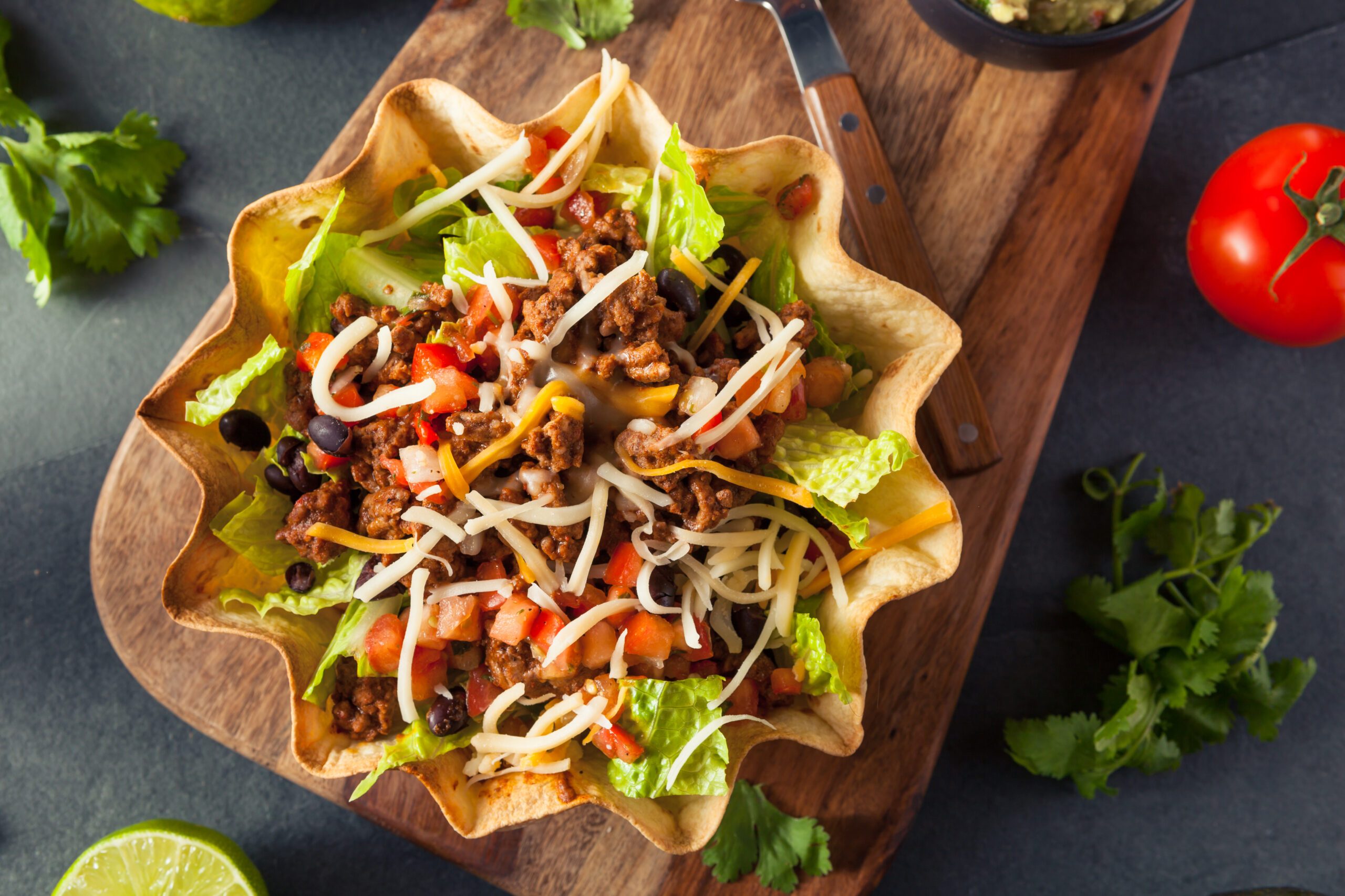 Taco salad in a tortilla bowl with beef, cheese, and lettuce