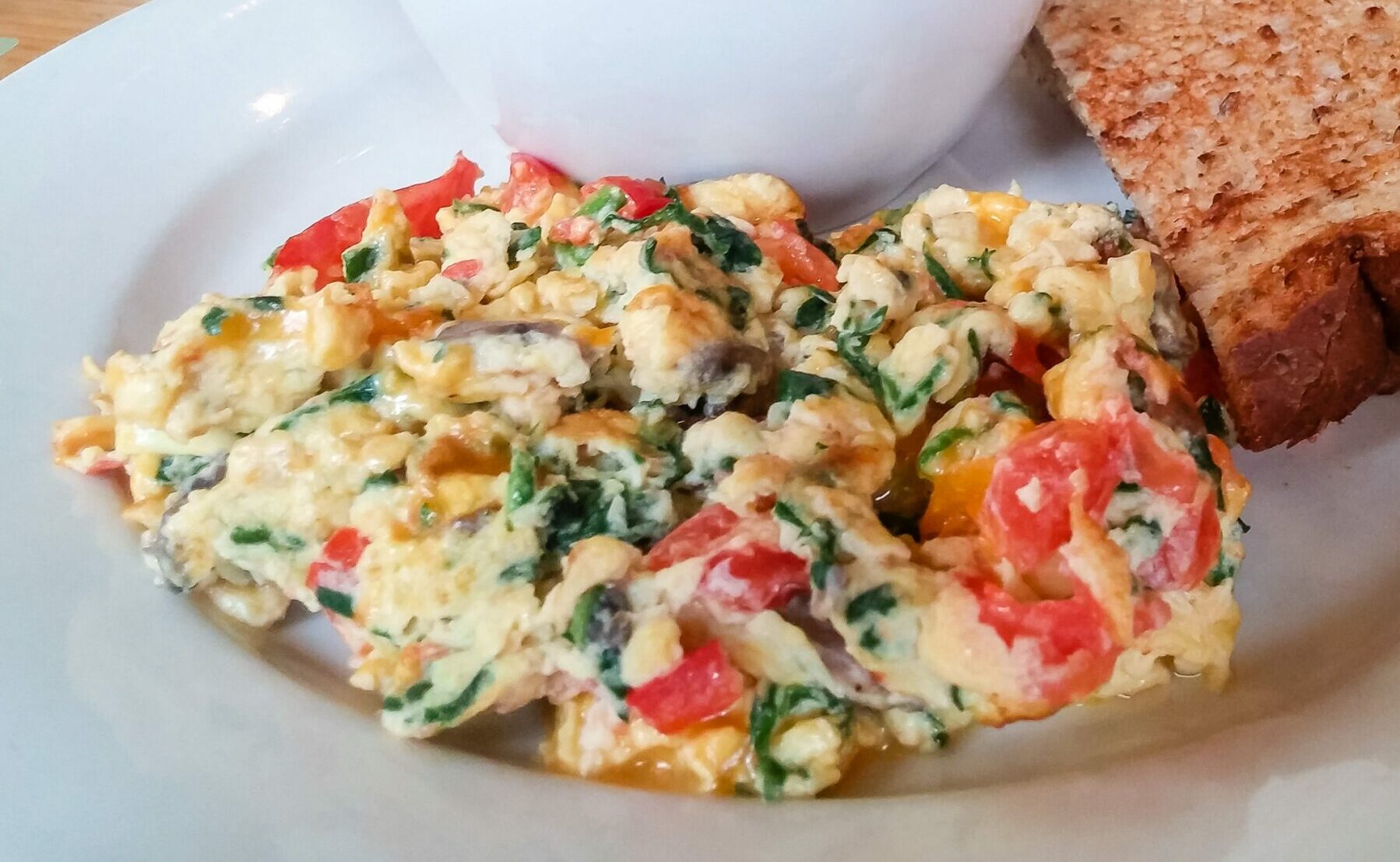 Vegetable scramble with grits and toast on a table