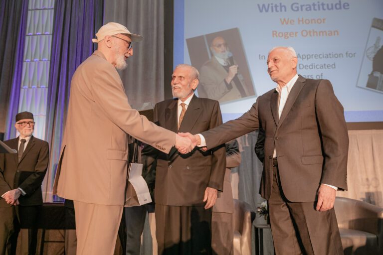 Roger Othman and Dr. Chaudry shake hands while other board members look on