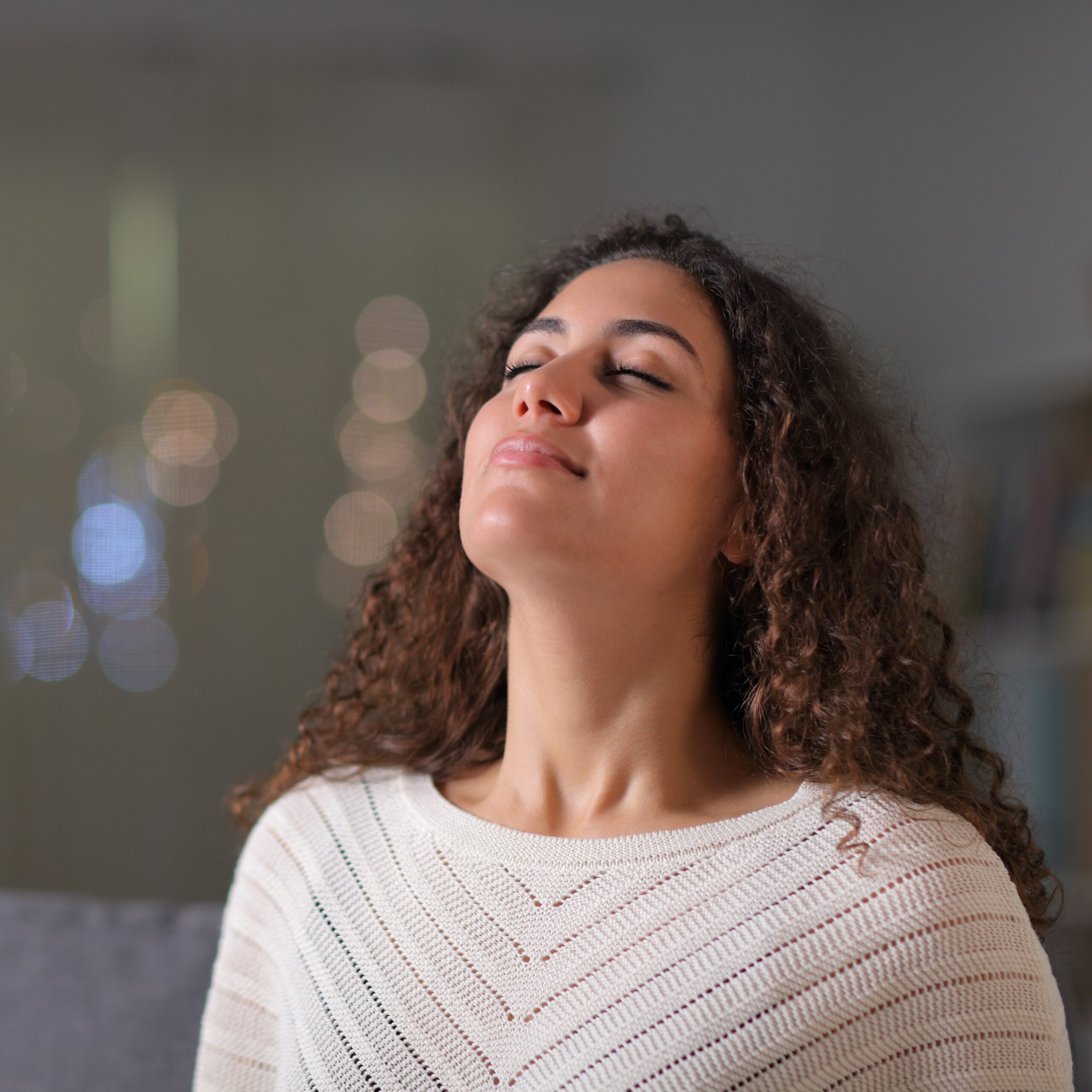 Relaxed woman breathing fresh air sitting on a couch in a living room