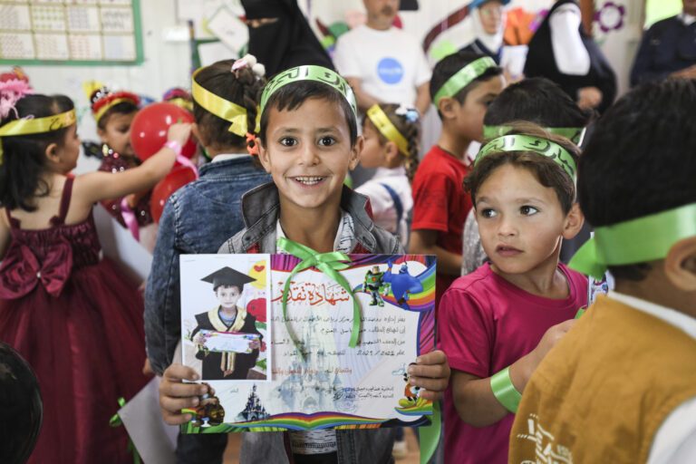 Some students are shown proudly displaying their newly acquired diplomas.