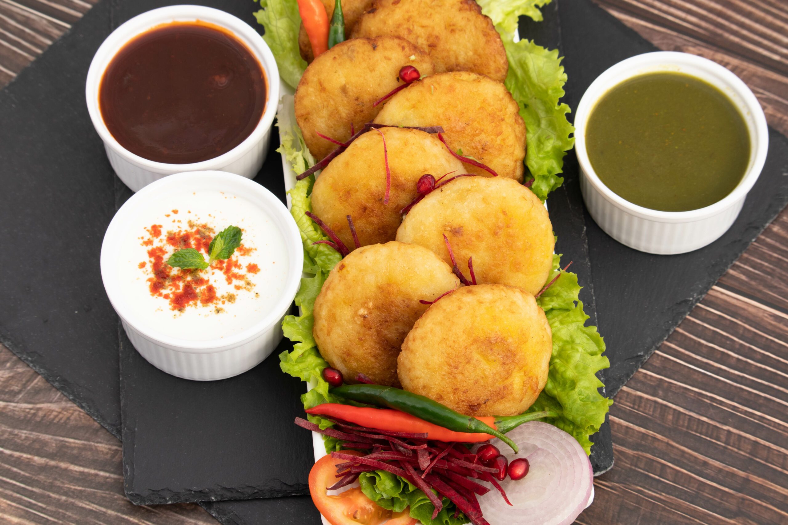 Decorated Platter Of Delicious Aloo Tikki Also Known As Alu Ki Tikkia A Seasoned Boiled Mashed Potato Cutlet Or Patties Served With Dhaniya Pudina Green Chutney Chatpata Imli Sauce And Dahi Masala