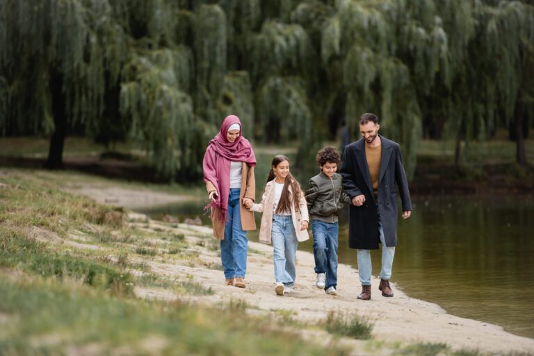 Smiling muslim kids walking near parents and lake in park