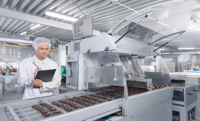 Chocolate factory man worker inspecting production line conveyor with sweets candy. Concept control food industry.