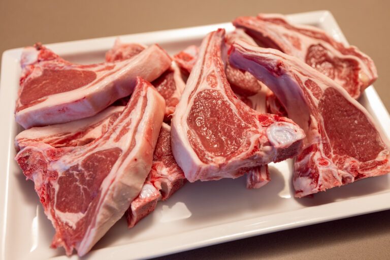 Raw lamb chops on a white plate in selective focus The marbled pink meat and visible fat emphasize the high quality and nutritional value of the fresh lamb cuts