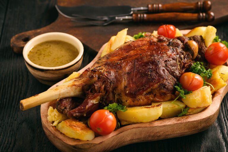 Slow baked lamb leg with potatoes and sauce.